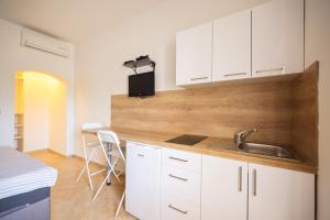 a kitchen with white cabinets and a sink and a bed at Apartments Marina in Petrcane