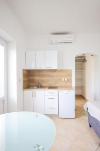 una cocina con armarios blancos y fregadero en Apartments Marina en Petrcane