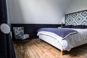 1 dormitorio con 1 cama y 1 silla en La Villa de l'Etoile 10 personnes, en Forges-les-Eaux