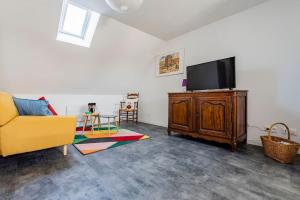 ein Wohnzimmer mit einem gelben Sofa und einem Flachbild-TV in der Unterkunft Duplex LUTON 4 in Reims