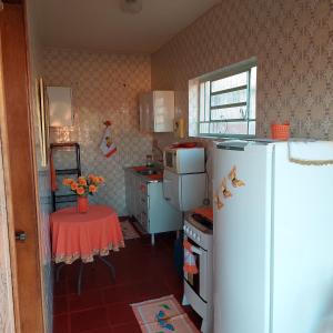 a small kitchen with a white refrigerator and a table at Recanto Panapaná - suítes in Águas de São Pedro