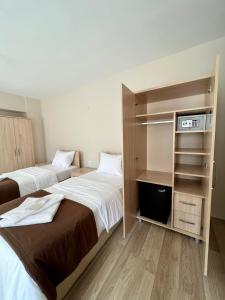 a hotel room with two beds and a book shelf at Akar Pansiyon in Canakkale