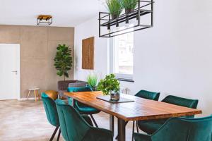 瓦爾內明德的住宿－Haus Shiralee - Das Ferienhaus Warnemünde，一间带木桌和绿色椅子的用餐室