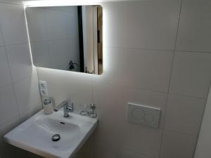 a white bathroom with a sink and a mirror at Appartement Design 2 in Altenstadt