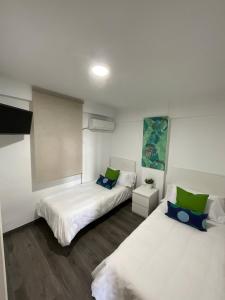 dwa łóżka w pokoju z biało-zielonym w obiekcie AYALA APARTAMENTO w Maladze