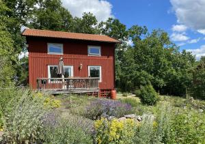 a red house with a balcony in a garden at Häradssätter Gård in Valdemarsvik