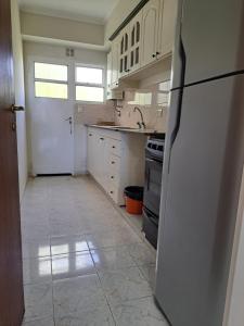 a kitchen with white cabinets and a refrigerator at Temporarios Roque Saenz Peña, Dto D in Puerto Madryn