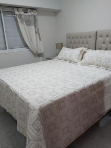 a large white bed in a bedroom with a window at Temporarios Roque Saenz Peña, Dto D in Puerto Madryn