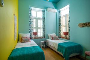 2 Betten in einem Zimmer mit blauen Wänden und Fenstern in der Unterkunft Historical city villa in Willemstad