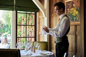 un hombre parado frente a una mesa con copas de vino en The Montagu Arms en Beaulieu