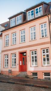 un gran edificio rosa con una puerta roja en Lieblingsapartment No.12 für bis zu 6 Gäste en Rostock