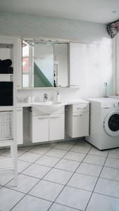 een witte badkamer met een wastafel en een wasmachine bij Lieblingsapartment No.12 für bis zu 6 Gäste in Rostock