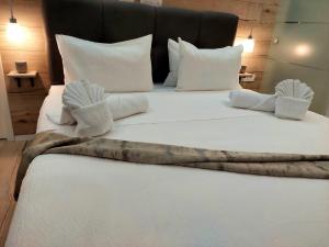 a large white bed with white pillows and blankets at V Apartment in Šibenik