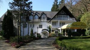 a large white house with an umbrella on a driveway at Park Hotel am Schloss in Ettringen