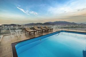 a pool on the roof of a building with mountains in the background at An Vista Hotel in Nha Trang