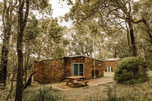 eine Blockhütte mit Picknicktisch im Wald in der Unterkunft Gum Grove Chalets in Denmark