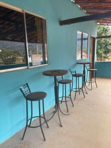 een rij tafels en stoelen tegen een blauwe muur bij Chalé Agreste in Santana do Riacho