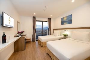 um quarto de hotel com duas camas e uma janela em An Vista Hotel em Nha Trang