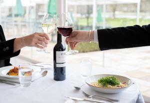 dos personas sentadas en una mesa con una copa de vino en Phyllis Court Members Club, en Henley on Thames