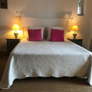 1 dormitorio con 1 cama blanca y 2 almohadas rosas en Le Logis, en Gordes