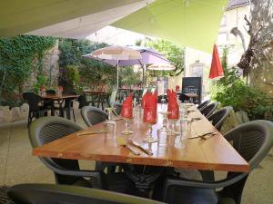 una mesa de madera en un restaurante con sillas y sombrillas en Hôtel Restaurant des Voyageurs, en Nant