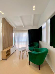 una sala de espera con sillas verdes y una mesa en Qeparo Napolon Complex, en Qeparo