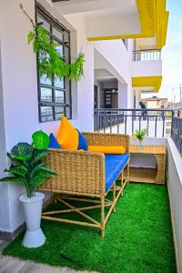 a balcony with a wicker couch and a green rug at The Presidential Suite in Ruiru