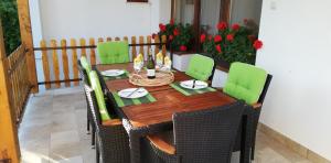 a wooden table with green chairs on a balcony at Vicky's House in Bük