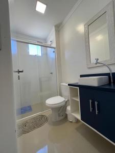a bathroom with a shower and a toilet and a sink at Apartamento Novo e Confortável in Itapema