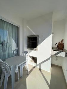 a white room with a table and chairs and a fireplace at Apartamento Novo e Confortável in Itapema