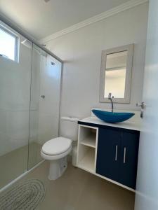 a bathroom with a sink and a toilet and a mirror at Apartamento Novo e Confortável in Itapema