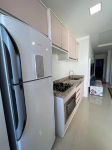 伊塔佩馬的住宿－Apartamento Novo e Confortável，白色的厨房配有冰箱和炉灶。