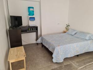 1 dormitorio con 1 cama, TV y mesa en CasaBlanca alq. Deptos en San Salvador de Jujuy