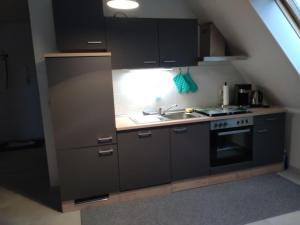 a kitchen with black cabinets and a sink and a stove at Ferienapartment-Loebau-Stadt-und-Messenah in Löbau