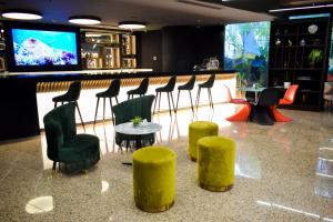 um bar com cadeiras e mesas verdes e uma televisão em Lidotel Caracas em Caracas