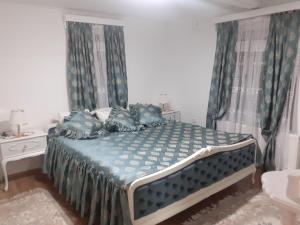 Schlafzimmer mit einem Bett mit blauer Bettwäsche und Kissen in der Unterkunft BELA VILA MIJALKOV 