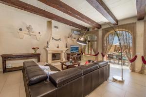 a living room with a leather couch and a fireplace at LeVecca Village House 1 - Gladiola in Għasri