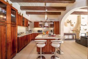 una cocina con armarios de madera y una isla con taburetes. en LeVecca Village House 1 - Gladiola en Għasri