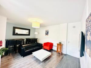a living room with a black couch and a red chair at Reims Sherpa Lodge in Reims