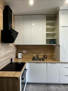 a kitchen with white cabinets and a sink at Apartament na Nowej Cukrowni in Szczecin