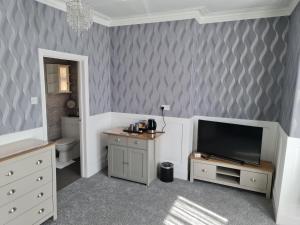 a living room with a television and a bathroom at Marden guest house in Weymouth