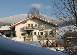 une maison recouverte de neige devant une montagne dans l'établissement Ferienwohnungen Altmann Steffi und Herbert, à Lam