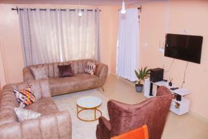 a living room with two couches and a flat screen tv at Royal Palms Executive 2& 1 bedrooms BNB Wote town in Wote +3 photos