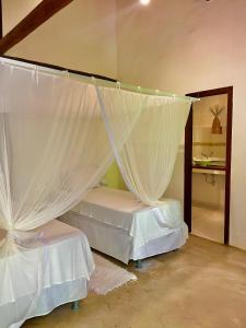 1 dormitorio con 2 camas con cortinas blancas en Pousada Villa Bahia en Trancoso