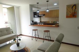 sala de estar con sofá y sillas y cocina en Apartamento Completo Poblado - Ubicacion Central con Parqueadero, en Medellín