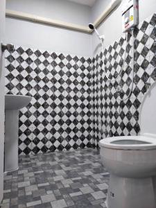 a bathroom with a toilet and a checkered shower curtain at บ้านทุ่ง เคียงบึง รีสอร์ท in Ban Don Klang