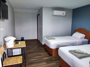 a hotel room with two beds and a table at บ้านทุ่ง เคียงบึง รีสอร์ท in Ban Don Klang