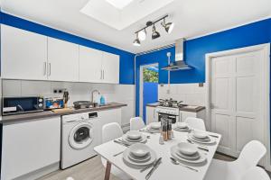 cocina con paredes azules, mesa blanca y sillas en 3BR Stylish Modern House Oxford en Oxford