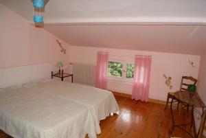 a bedroom with a bed and a window with pink curtains at Durand Yves in Régnié