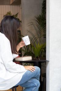 a woman sitting at a table drinking a cup of coffee at The Modernist Thessaloniki in Thessaloniki